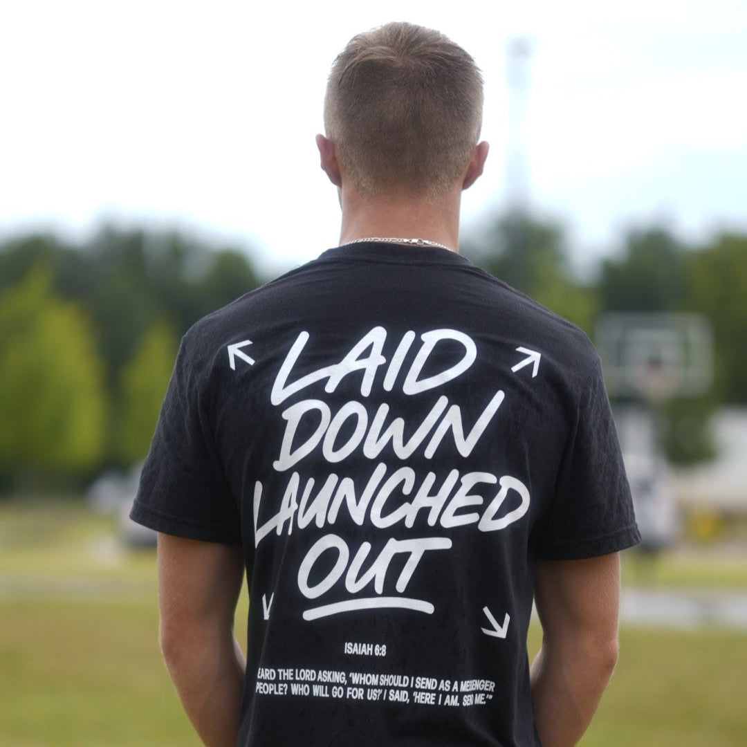 Person wearing a black t-shirt with white text outdoors